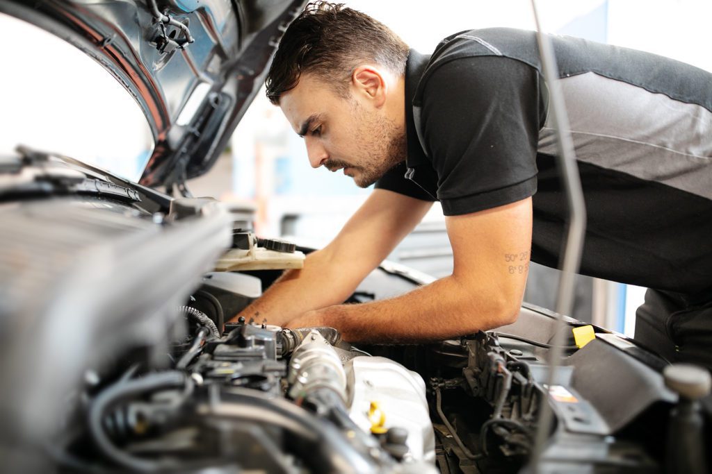 Techniker überprüft Motor eines Fahrzeugs Garage Servais